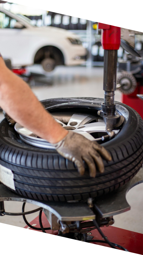 A man is repairing a tire in a well-lit garage, surrounded by tools and equipment.