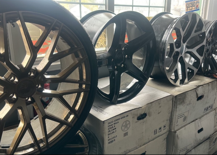 A row of various wheels and rims displayed on top of boxes in a warehouse setting.