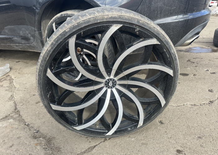 A black car with a visibly damaged wheel, indicating potential issues with mobility or safety.